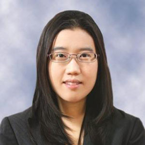 A woman with dark hair and glasses smiles at the camera