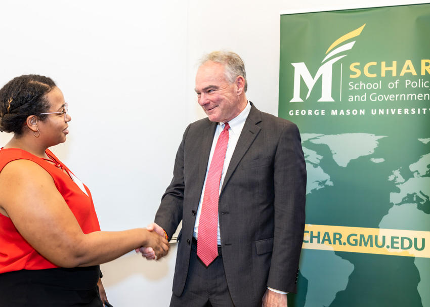 U.S. Senator Tim Kaine (D. Va.) greets a graduate student and extends a handshake.